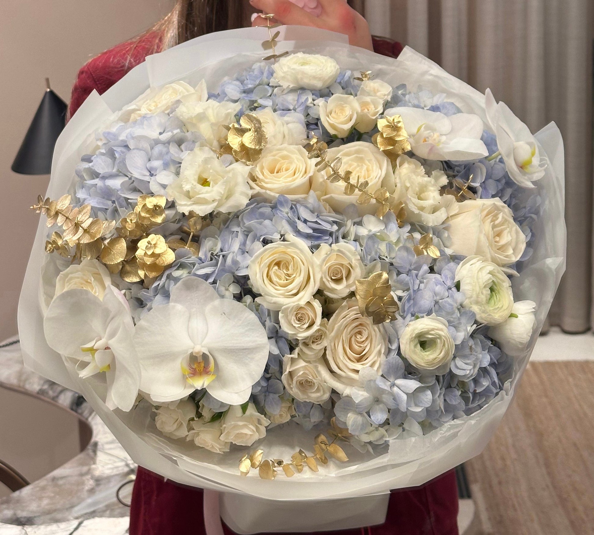 Oversized pastel bouquet with soft blue hydrangeas, roses, and gold leaf accents – a grand floral arrangement.