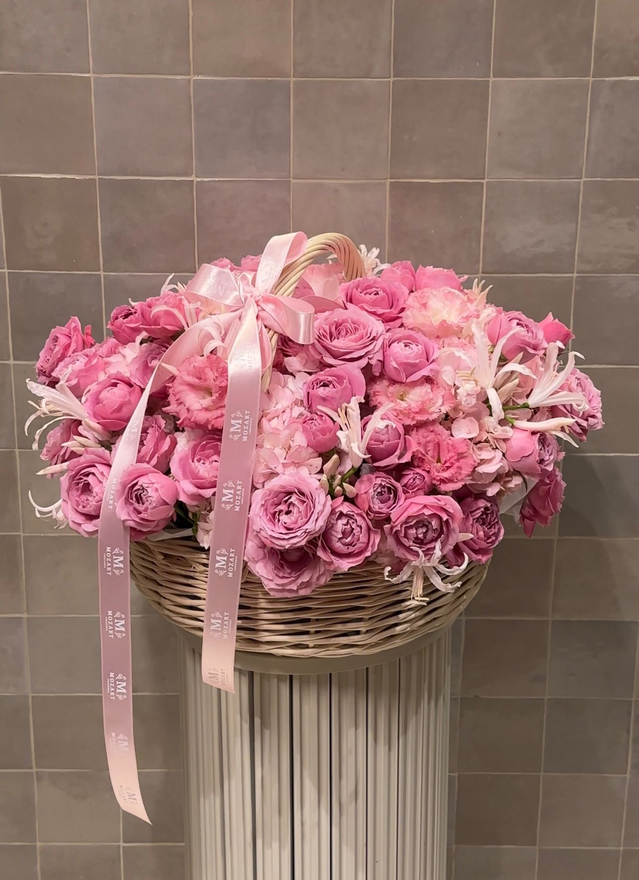 Large basket of hot pink and blush florals with ribbons – playful and lavish floral gift.