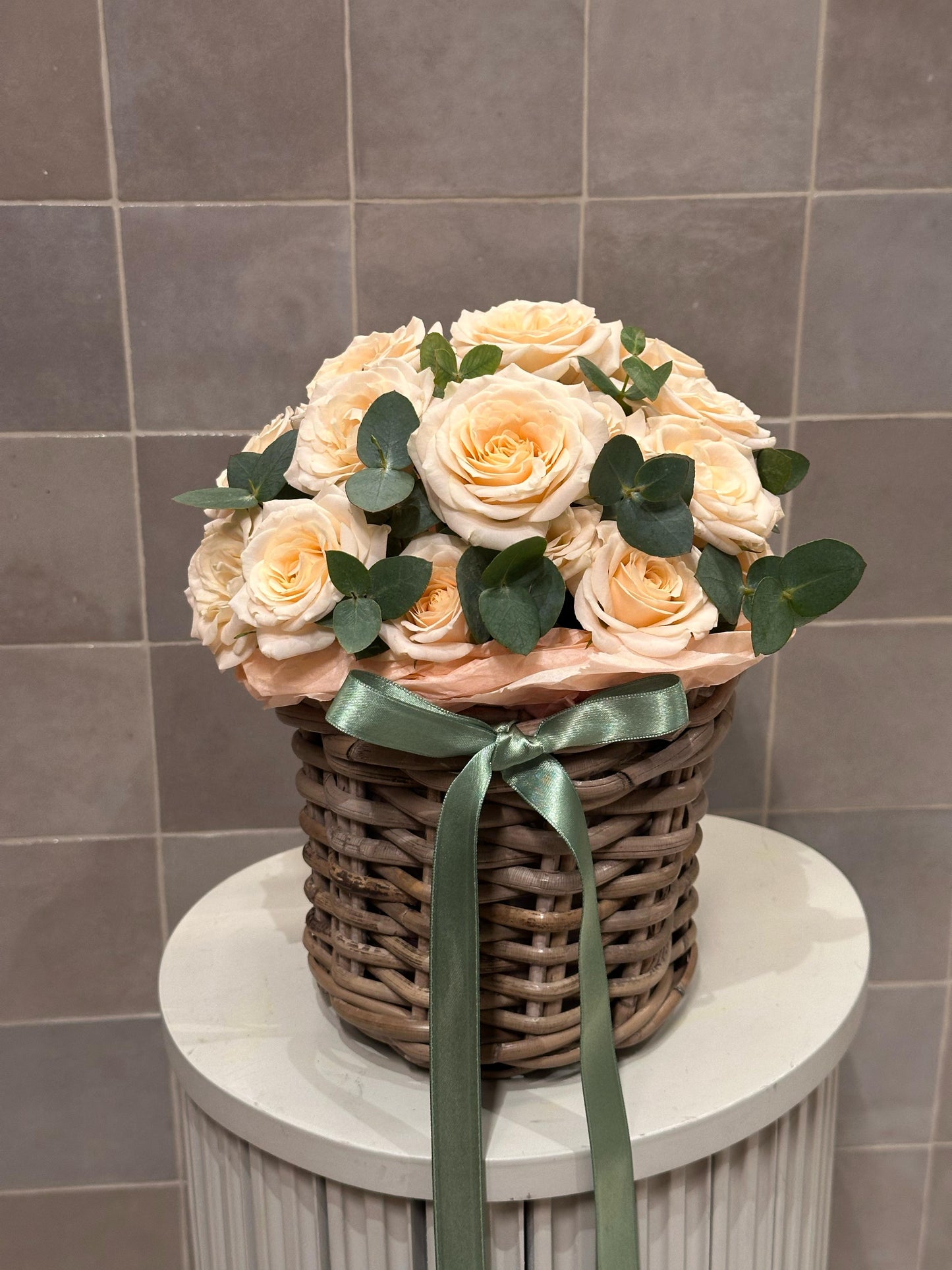 Peach-toned roses in a woven basket – a timeless floral piece from Mozart Concierge